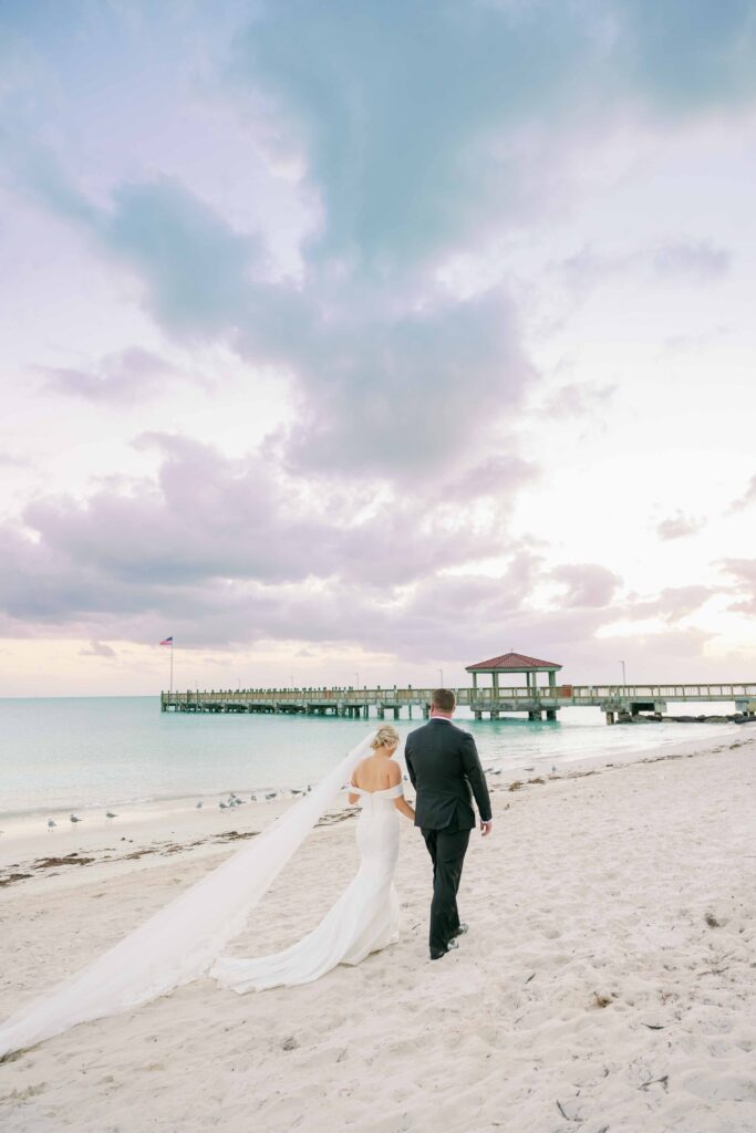 A bride and groom walking along the beach at The Casa Marina in Key West.