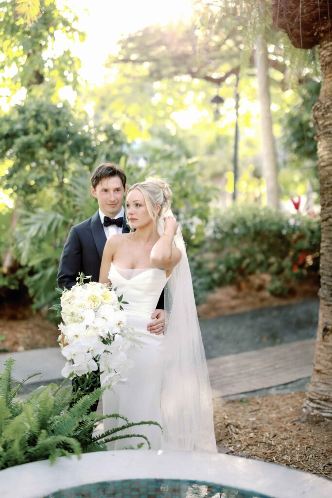 A bride and groom posing for photos in the garden of The Ernest Hemingway Home